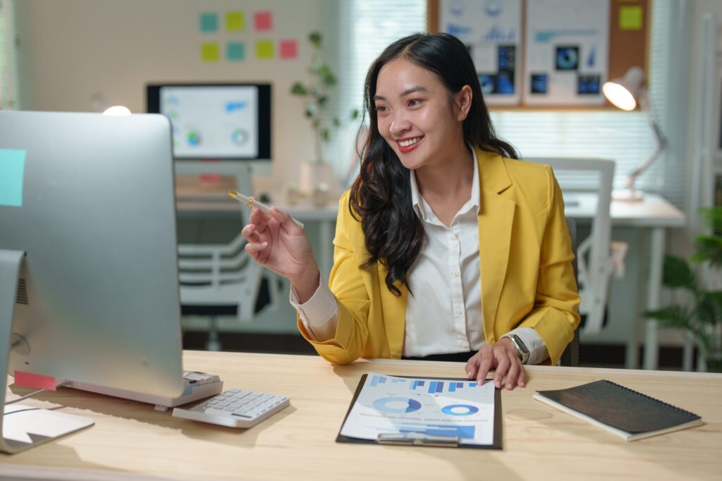 Young professional woman working late, reviewing financial data and using computer to analyze market