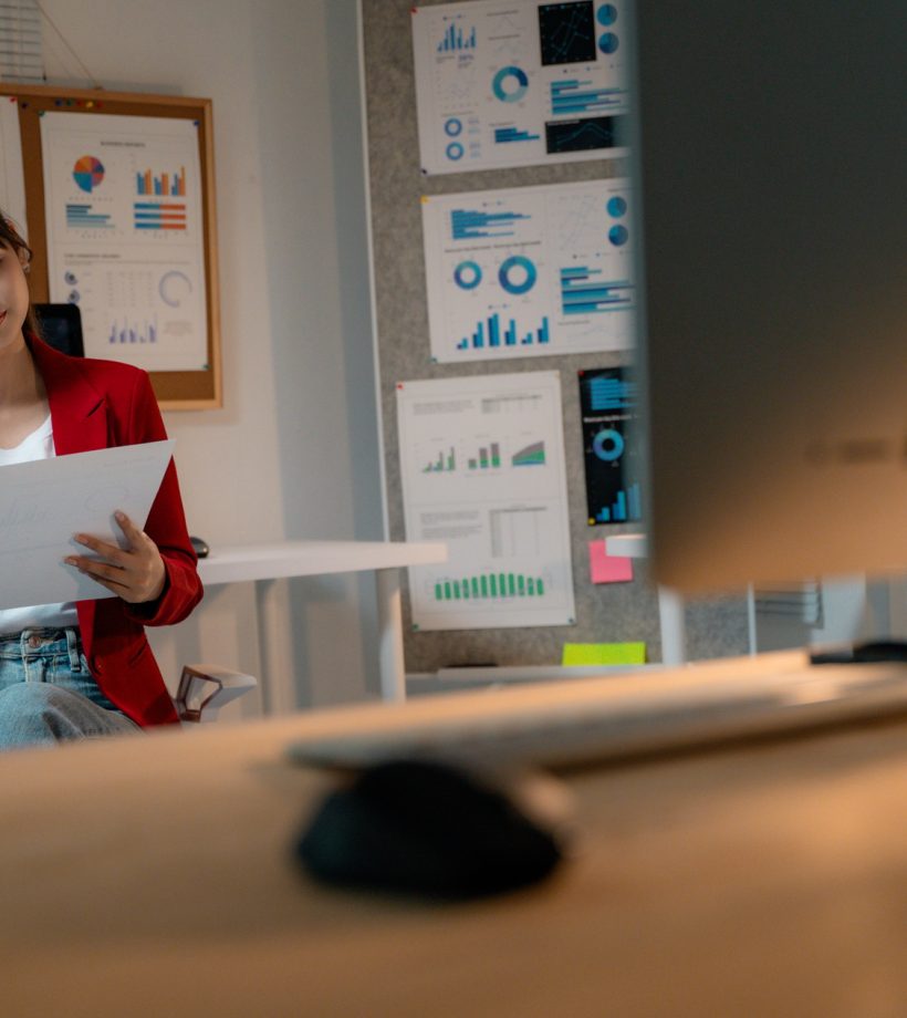 Asian businesswoman reviewing financial report and touching her head while working.